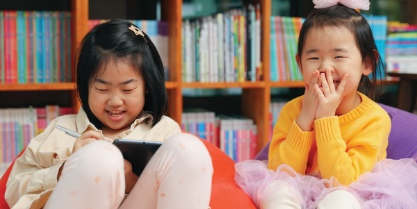 two girls giggle in the library during story time