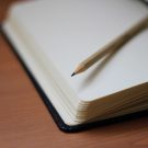 Sharpened pencil lying on open notebook