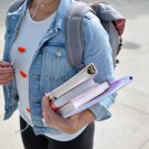 Person with a backpack holding a stack of books
