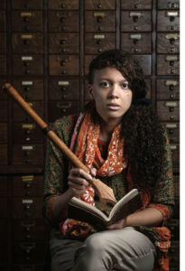 Portland Poet Laureate, Maya Williams, pretends to write the comically large official poet laureate pen in a notebook