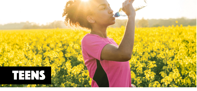 woman drinking water while exercising in a field