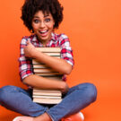 woman smiling and hugging a stack of books