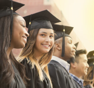 College graduates in caps and gowns stand in a line.