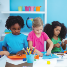 kids stand at a table doing various crafts