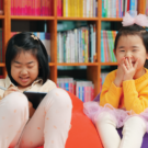 two girls giggle in the library during story time