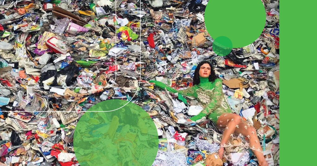 woman in elegant green dress lounges on a pile of trash at a landfill