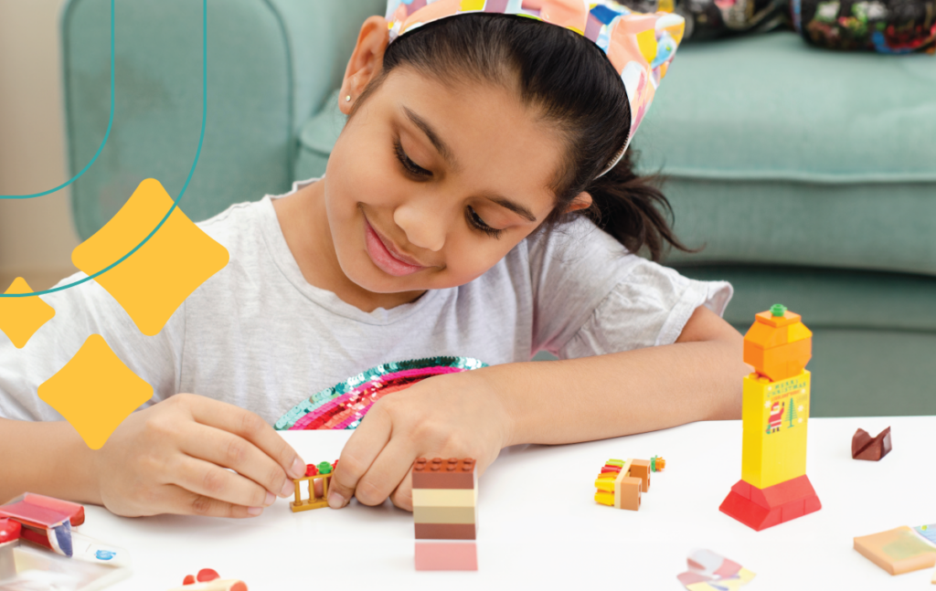 young girl plays with Legos at a table